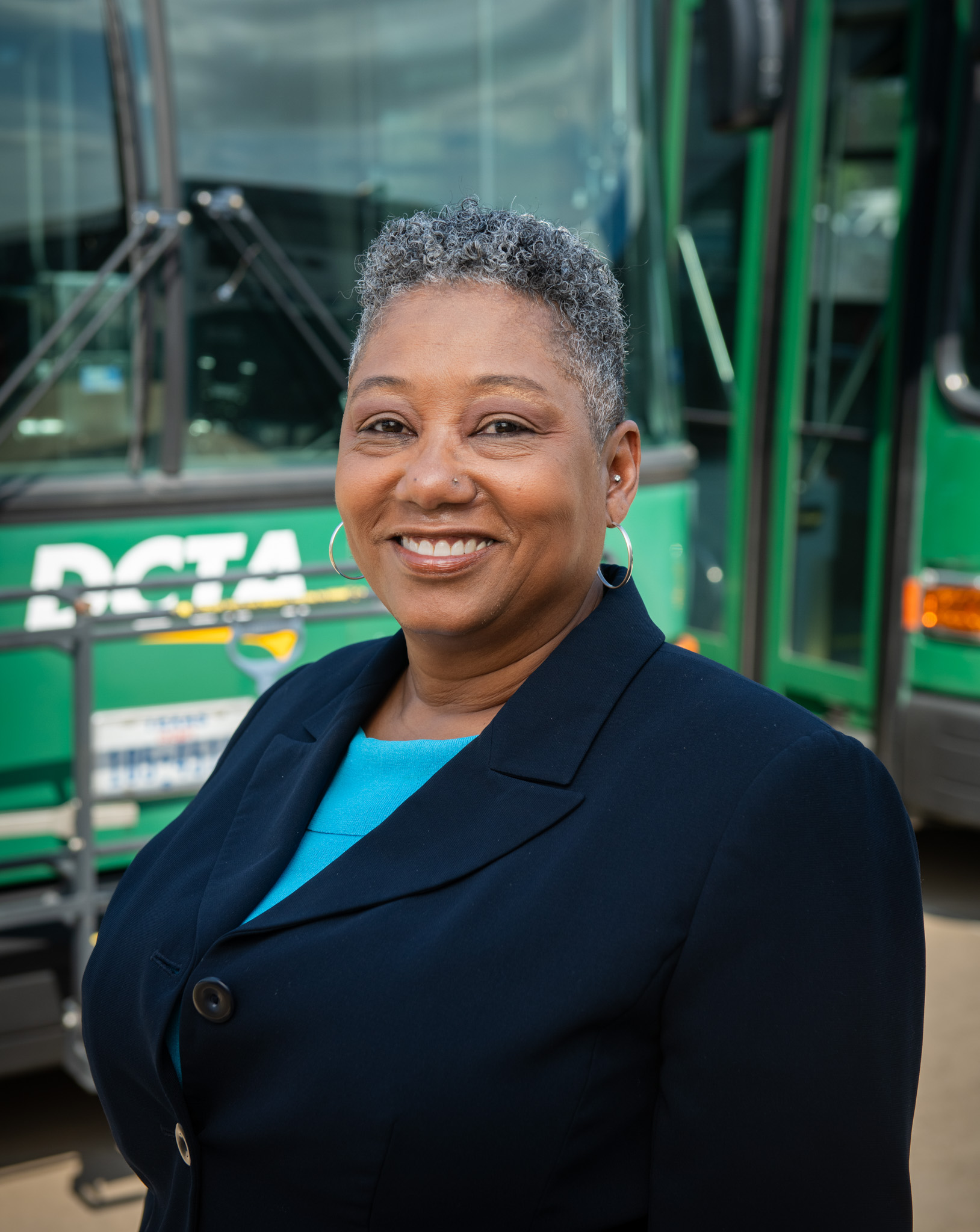 Headshot of Lisa Taylor, Vice President of Operations, in front of a DCTA Connect Bus