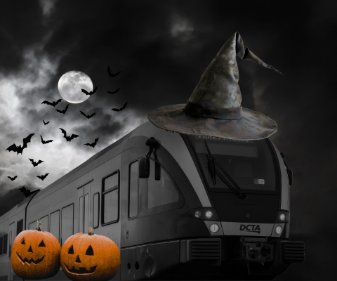 A black-and-white photo of the A-train wearing an oversized witch’s hat, with glowing jack-o’-lanterns below and bats crossing a full moon