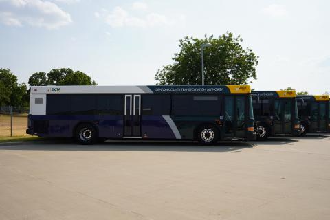 Three Connect buses from the Denton County Transportation Authority parked in a row under a sunny sky.